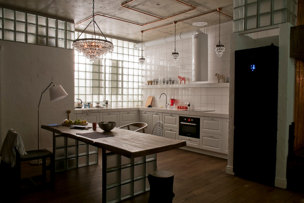 Offene Industrial Küche mit weißen Schränken, Arbeitsplatte aus Fliesen, Küchenrückwand in Weiß, schwarzen Elektrogeräten und dunklem Holzboden in Moskau