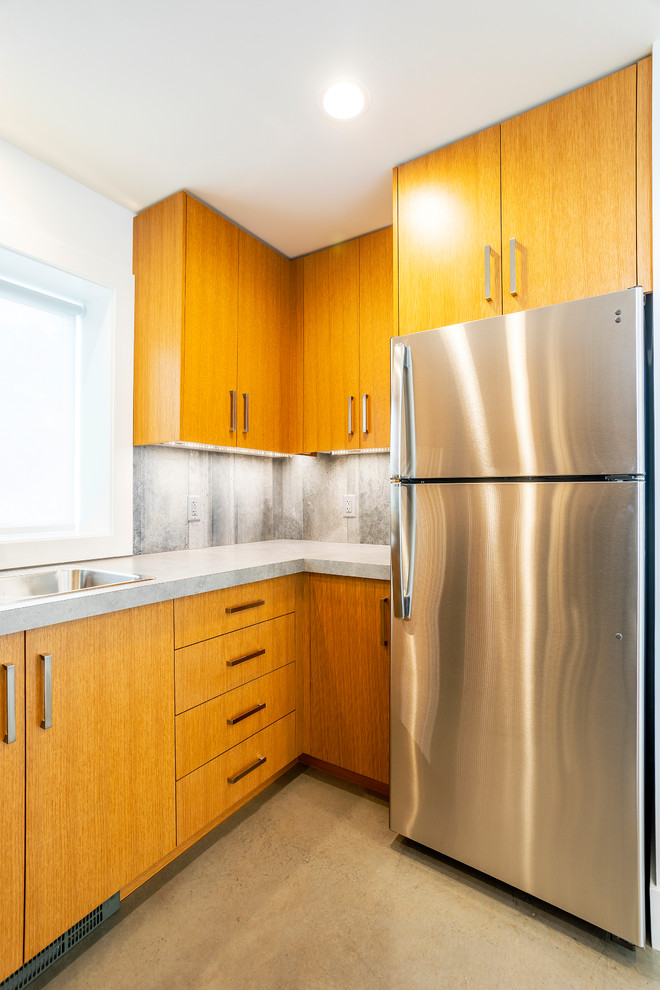 Modern inredning av ett litet grå grått kök, med en dubbel diskho, släta luckor, skåp i ljust trä, laminatbänkskiva, grått stänkskydd, stänkskydd i cementkakel, rostfria vitvaror, betonggolv, en halv köksö och grått golv