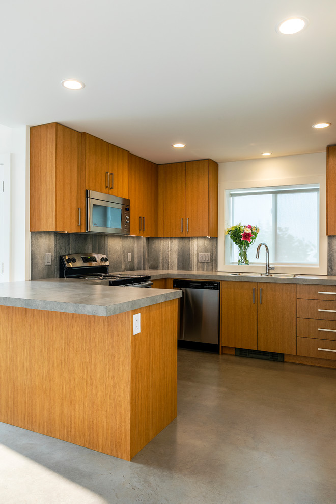 Bild på ett litet funkis grå grått kök, med en dubbel diskho, släta luckor, skåp i ljust trä, laminatbänkskiva, grått stänkskydd, stänkskydd i cementkakel, rostfria vitvaror, betonggolv, en halv köksö och grått golv