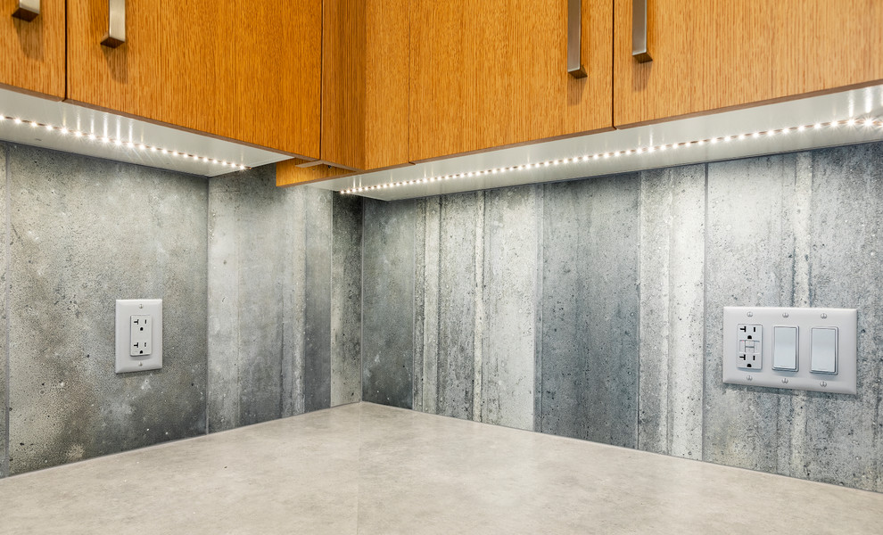 Inredning av ett modernt litet grå grått kök, med en dubbel diskho, släta luckor, skåp i ljust trä, laminatbänkskiva, grått stänkskydd, stänkskydd i cementkakel, rostfria vitvaror, betonggolv, en halv köksö och grått golv