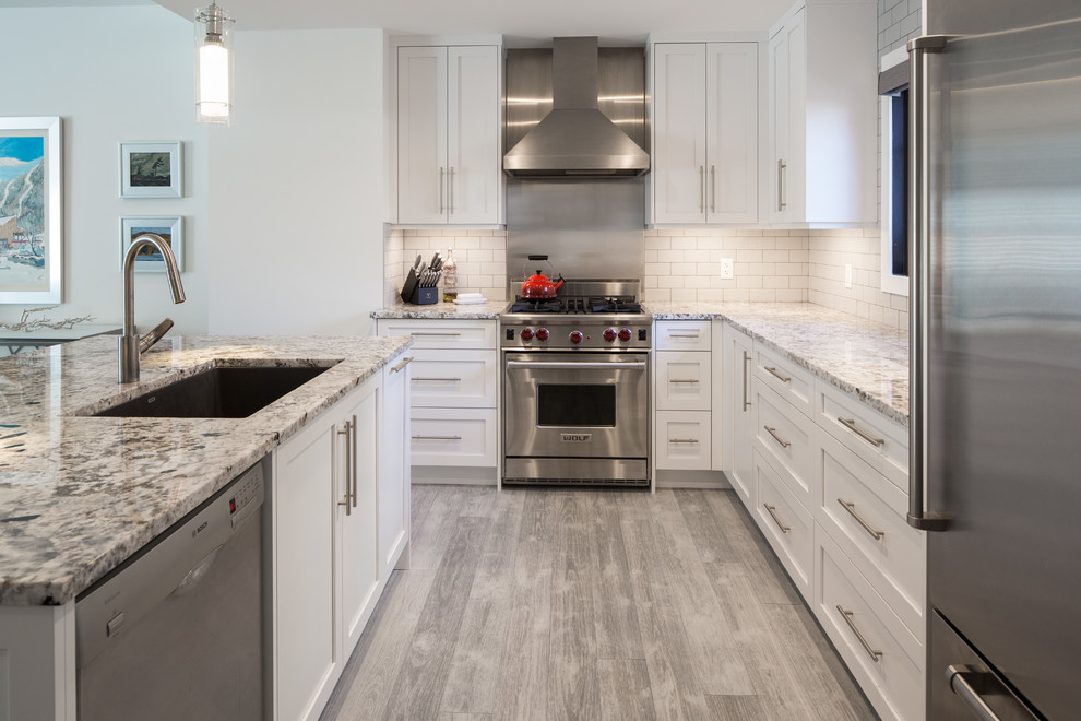 Small minimalist l-shaped light wood floor and gray floor eat-in kitchen photo in Calgary with an undermount sink, shaker cabinets, white cabinets, granite countertops, white backsplash, ceramic backsplash, stainless steel appliances and an island