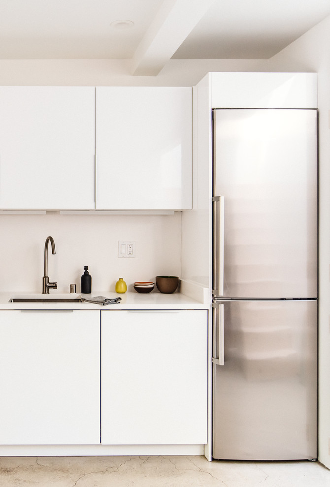 Idéer för att renovera ett mellanstort funkis linjärt kök och matrum, med en dubbel diskho, släta luckor, vita skåp, bänkskiva i koppar, vitt stänkskydd, rostfria vitvaror och betonggolv