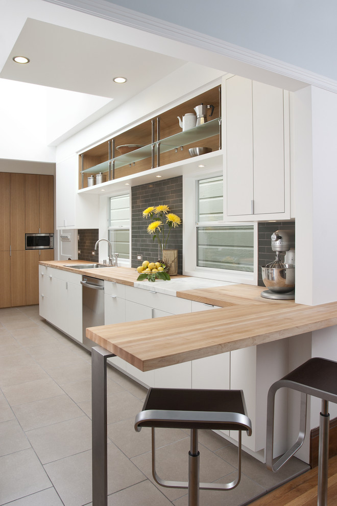 Inspiration for a modern kitchen in San Francisco with flat-panel cabinets, stainless steel appliances, wood worktops, white cabinets, grey splashback and metro tiled splashback.