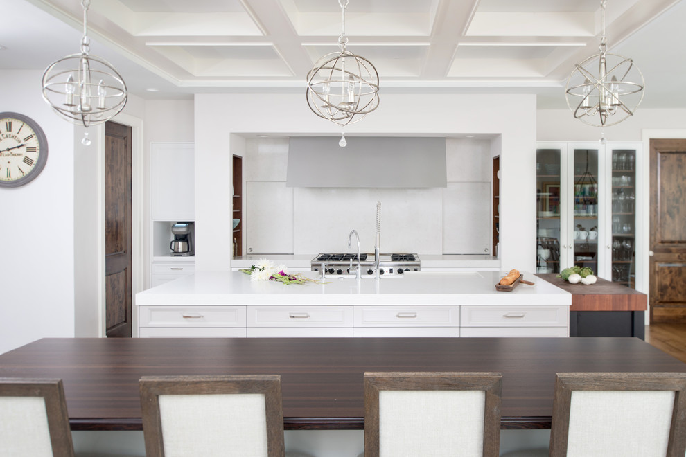 This is an example of an expansive classic galley kitchen/diner in Kansas City with a belfast sink, recessed-panel cabinets, white cabinets, engineered stone countertops, white splashback, stone slab splashback, stainless steel appliances, medium hardwood flooring and multiple islands.