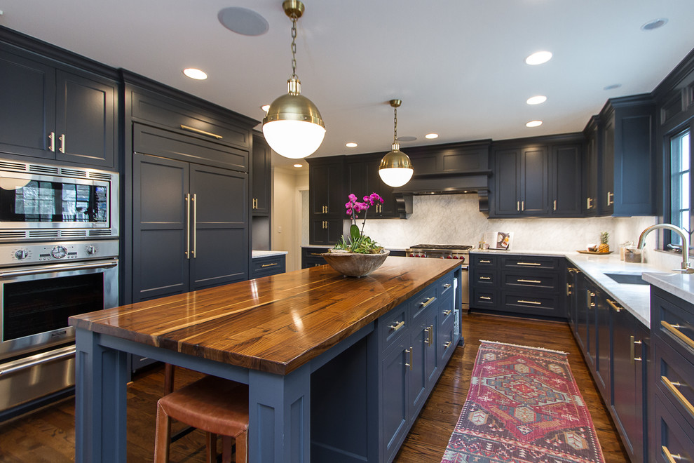 Classic l-shaped kitchen in Orlando with recessed-panel cabinets, blue cabinets, an island, a submerged sink, wood worktops, grey splashback, stainless steel appliances and medium hardwood flooring.