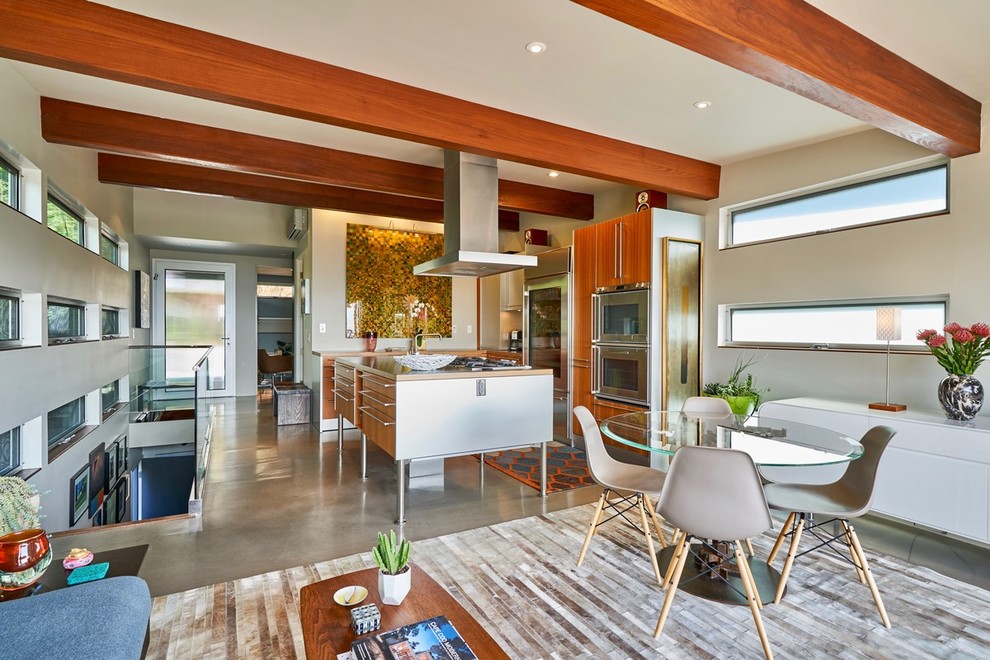 サンディエゴにある高級な小さなミッドセンチュリースタイルのおしゃれなキッチン (フラットパネル扉のキャビネット、中間色木目調キャビネット、ステンレスカウンター、シルバーの調理設備、コンクリートの床、グレーの床) の写真