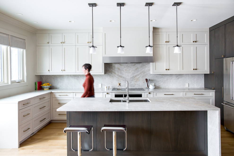 Inspiration for a transitional l-shaped light wood floor kitchen remodel in Calgary with a double-bowl sink, shaker cabinets, white cabinets, stone slab backsplash, stainless steel appliances, an island and white countertops