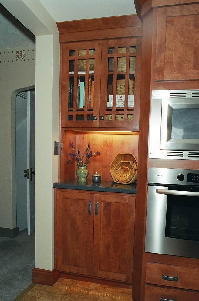 Cette image montre une petite cuisine parallèle rustique en bois brun fermée avec un évier encastré, un placard à porte shaker, un plan de travail en surface solide, une crédence bleue, un électroménager en acier inoxydable et un sol en liège.