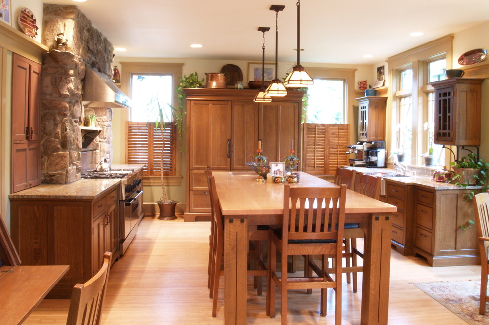 Example of a large arts and crafts u-shaped light wood floor eat-in kitchen design in Philadelphia with a farmhouse sink, medium tone wood cabinets, granite countertops, shaker cabinets, stone slab backsplash, paneled appliances and an island