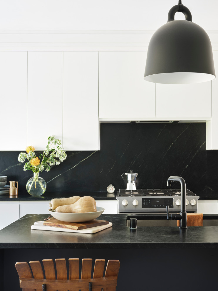 Photo of a medium sized scandinavian l-shaped open plan kitchen in San Francisco with a submerged sink, flat-panel cabinets, white cabinets, soapstone worktops, black splashback, stone tiled splashback, stainless steel appliances, an island and black worktops.