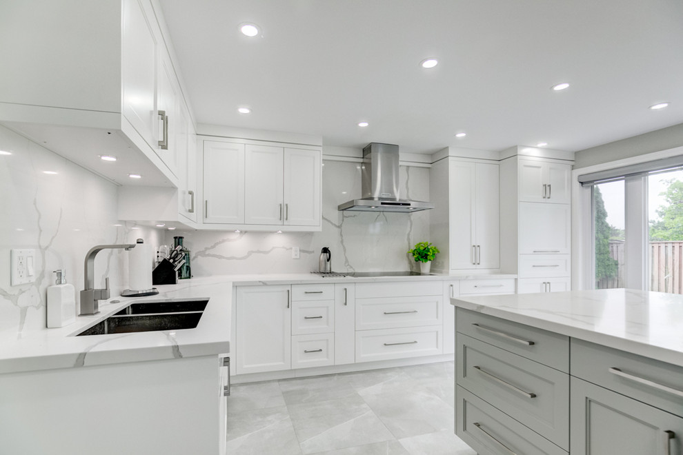 Foto på ett stort funkis vit kök, med en undermonterad diskho, skåp i shakerstil, vita skåp, marmorbänkskiva, vitt stänkskydd, stänkskydd i sten, rostfria vitvaror, marmorgolv, en köksö och grått golv