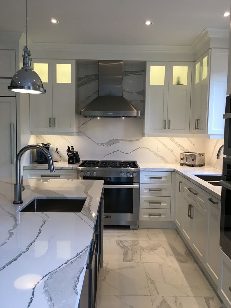 Design ideas for a large classic l-shaped enclosed kitchen in Toronto with a submerged sink, shaker cabinets, white cabinets, engineered stone countertops, white splashback, stone slab splashback, stainless steel appliances, porcelain flooring, an island, white floors and white worktops.