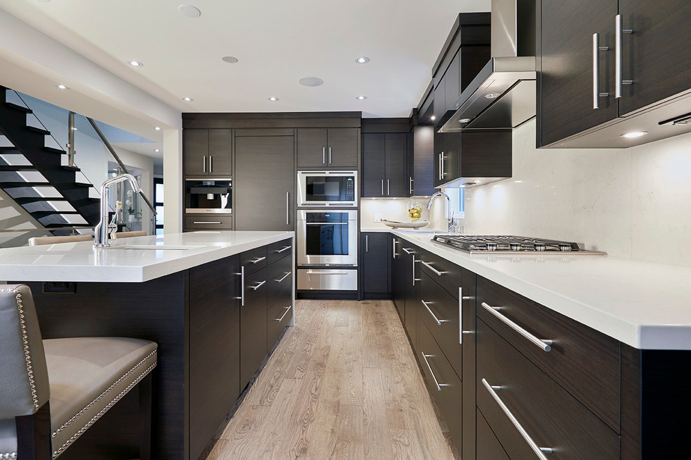 Eat-in kitchen - mid-sized modern l-shaped light wood floor eat-in kitchen idea in Toronto with an undermount sink, flat-panel cabinets, dark wood cabinets, solid surface countertops, white backsplash, stone slab backsplash, stainless steel appliances and an island