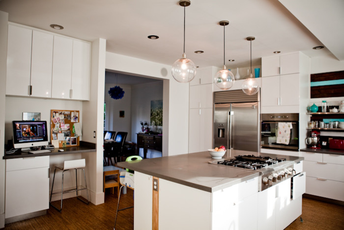 Immagine di una cucina contemporanea chiusa e di medie dimensioni con lavello sottopiano, ante lisce, ante bianche, elettrodomestici in acciaio inossidabile e pavimento in sughero