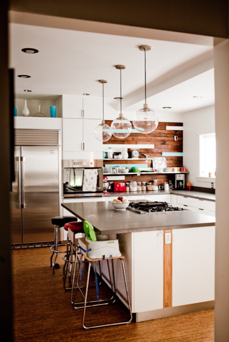 Foto på ett avskilt, mellanstort funkis l-kök, med en undermonterad diskho, släta luckor, vita skåp, rostfria vitvaror, korkgolv och en köksö