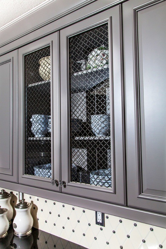 Klassisk inredning av ett kök, med en undermonterad diskho, luckor med upphöjd panel, grå skåp, granitbänkskiva, flerfärgad stänkskydd, rostfria vitvaror, mörkt trägolv och en köksö