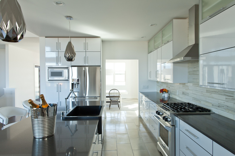 Example of a minimalist concrete floor open concept kitchen design in Other with a farmhouse sink, white cabinets, quartz countertops, stainless steel appliances and an island