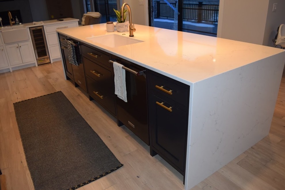 Example of a mid-sized country l-shaped light wood floor and brown floor kitchen design in Other with a farmhouse sink, beaded inset cabinets, white cabinets, quartz countertops, white backsplash, terra-cotta backsplash, paneled appliances, an island and white countertops