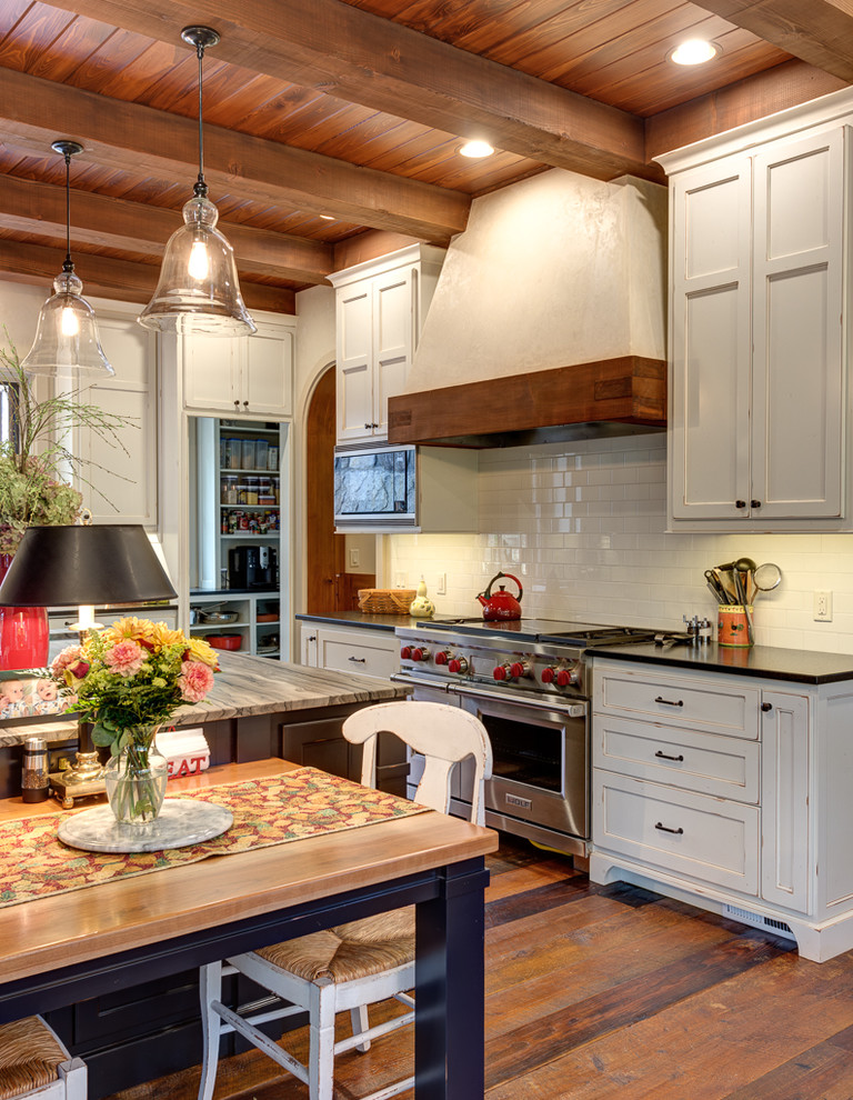 Exempel på ett stort rustikt kök, med en undermonterad diskho, skåp i shakerstil, vita skåp, marmorbänkskiva, vitt stänkskydd, stänkskydd i tunnelbanekakel, rostfria vitvaror, mellanmörkt trägolv och en köksö
