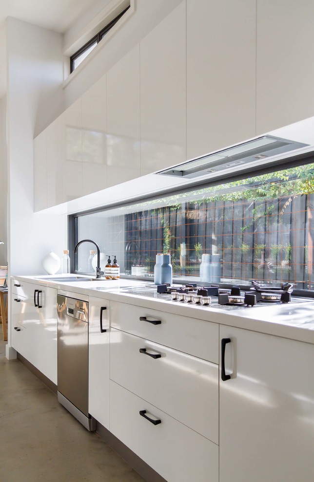 Пример оригинального дизайна: большая параллельная кухня-гостиная у окна в стиле модернизм с двойной мойкой, плоскими фасадами, белыми фасадами, столешницей из кварцевого агломерата, техникой из нержавеющей стали, бетонным полом и островом
