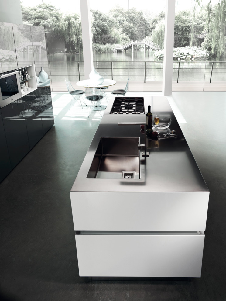 Immagine di una piccola cucina minimalista con ante lisce, elettrodomestici in acciaio inossidabile e pavimento in cemento