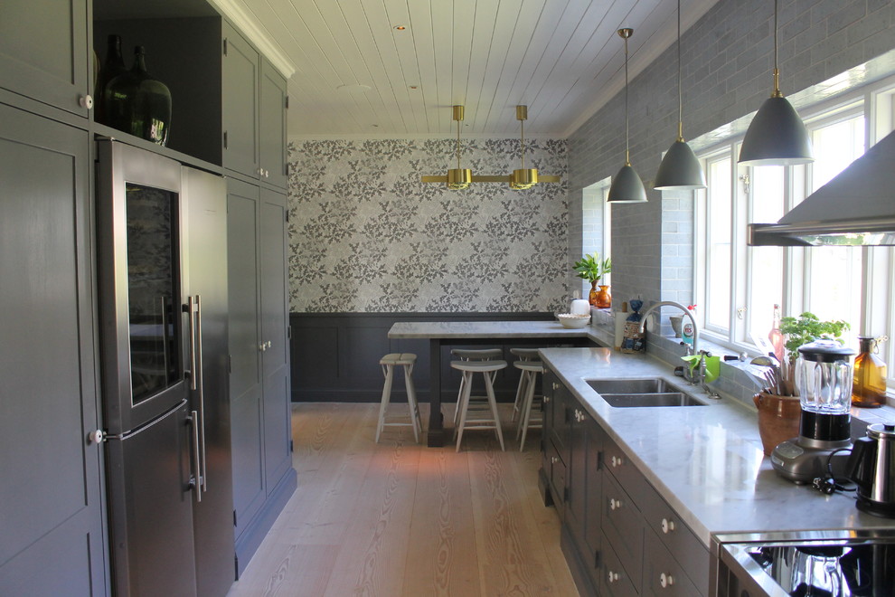Inredning av ett klassiskt mellanstort kök, med en dubbel diskho, luckor med upphöjd panel, grå skåp, marmorbänkskiva, rostfria vitvaror och mellanmörkt trägolv