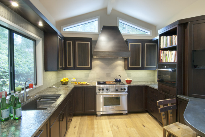 Immagine di una cucina minimal con lavello sottopiano, ante lisce, ante in legno bruno, top in granito, paraspruzzi beige, elettrodomestici in acciaio inossidabile, parquet chiaro e penisola
