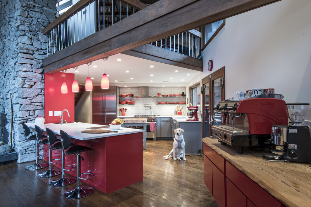Inspiration for a mid-sized contemporary u-shaped medium tone wood floor open concept kitchen remodel in Louisville with an undermount sink, flat-panel cabinets, red cabinets, quartz countertops, white backsplash, subway tile backsplash, stainless steel appliances and a peninsula
