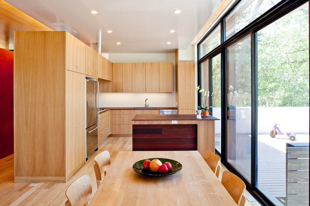 Foto di una cucina minimalista con lavello sottopiano, ante lisce, ante in legno chiaro, top in legno, elettrodomestici in acciaio inossidabile e parquet chiaro