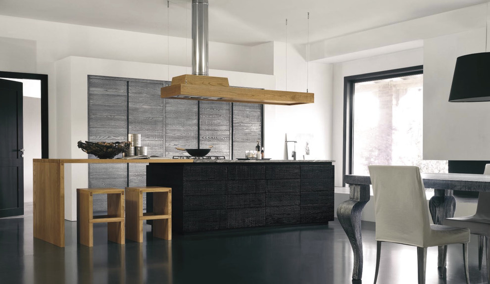 Eat-in kitchen - contemporary galley eat-in kitchen idea in London with wood countertops, flat-panel cabinets, black cabinets and paneled appliances