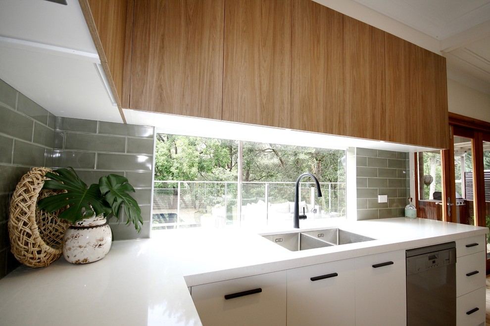 Idéer för att renovera ett mellanstort funkis vit vitt kök, med en undermonterad diskho, släta luckor, vita skåp, bänkskiva i kvarts, grönt stänkskydd, stänkskydd i tunnelbanekakel, rostfria vitvaror, mellanmörkt trägolv och brunt golv