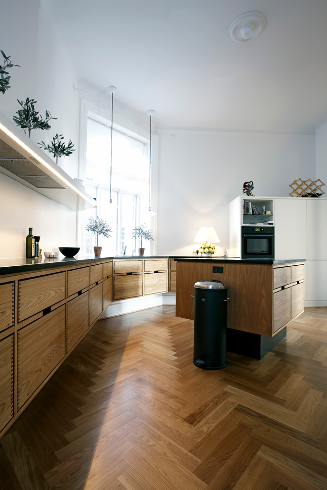 Esempio di una cucina minimalista con lavello sottopiano, ante in legno scuro, top in granito, paraspruzzi bianco e elettrodomestici in acciaio inossidabile