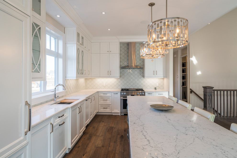 Inspiration for a large transitional l-shaped medium tone wood floor and brown floor kitchen remodel in Toronto with an undermount sink, recessed-panel cabinets, white cabinets, quartzite countertops, white backsplash, ceramic backsplash, paneled appliances and an island