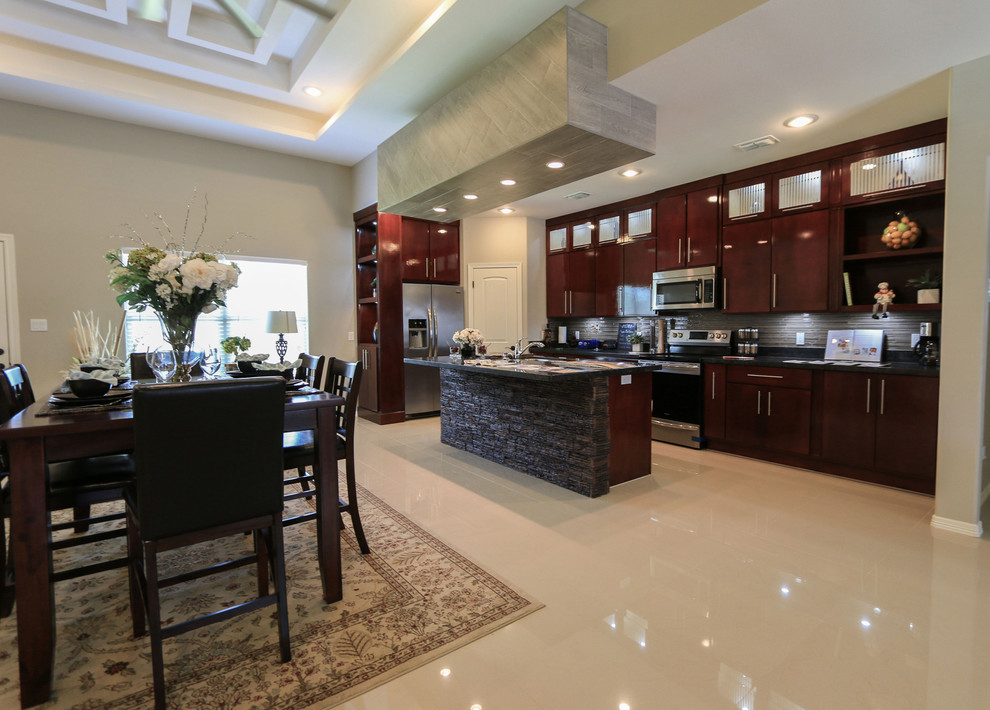 Example of a mid-sized tuscan single-wall open concept kitchen design in Other with flat-panel cabinets, dark wood cabinets, granite countertops, gray backsplash, ceramic backsplash, stainless steel appliances, an island and blue countertops