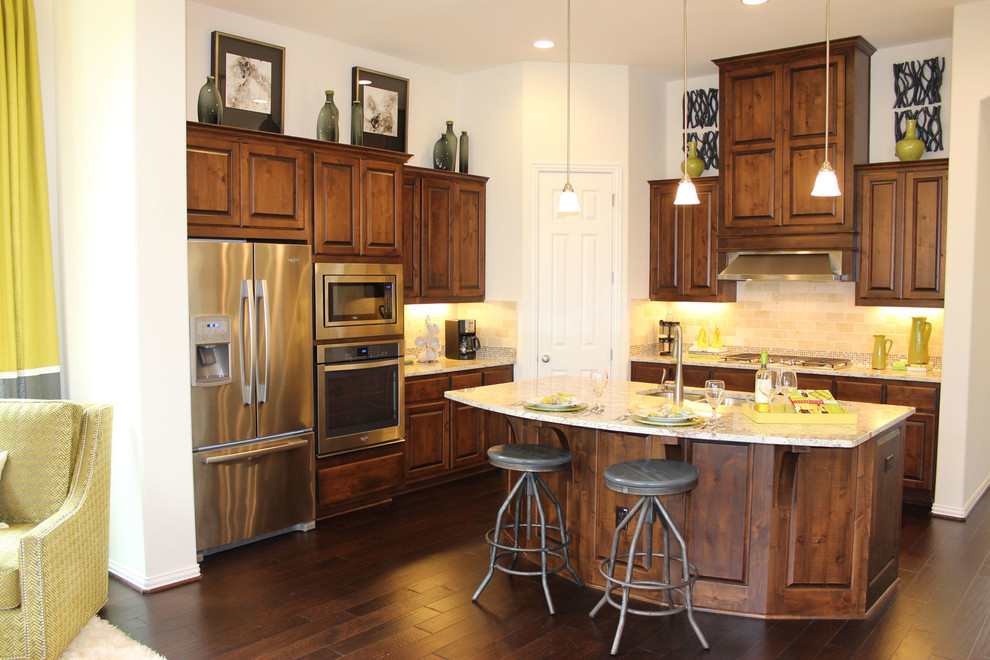 Photo of a large classic l-shaped open plan kitchen in Austin with a submerged sink, raised-panel cabinets, medium wood cabinets, granite worktops, beige splashback, stainless steel appliances, dark hardwood flooring and an island.