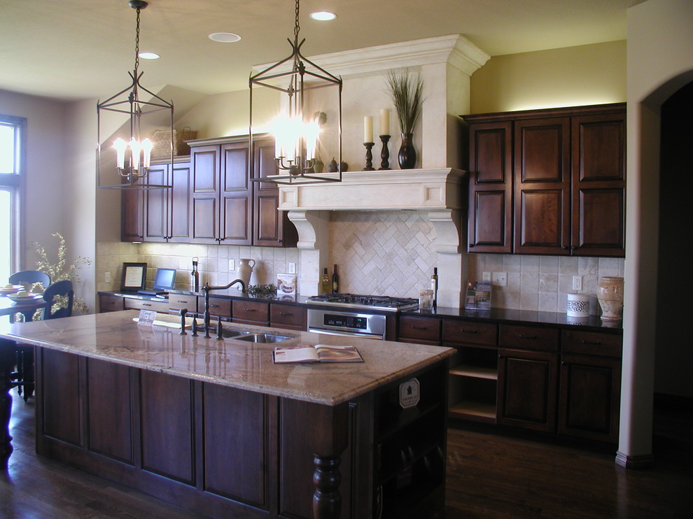 Inspiration for a large timeless galley dark wood floor eat-in kitchen remodel in Wichita with a double-bowl sink, raised-panel cabinets, dark wood cabinets, marble countertops, beige backsplash, terra-cotta backsplash, stainless steel appliances and an island
