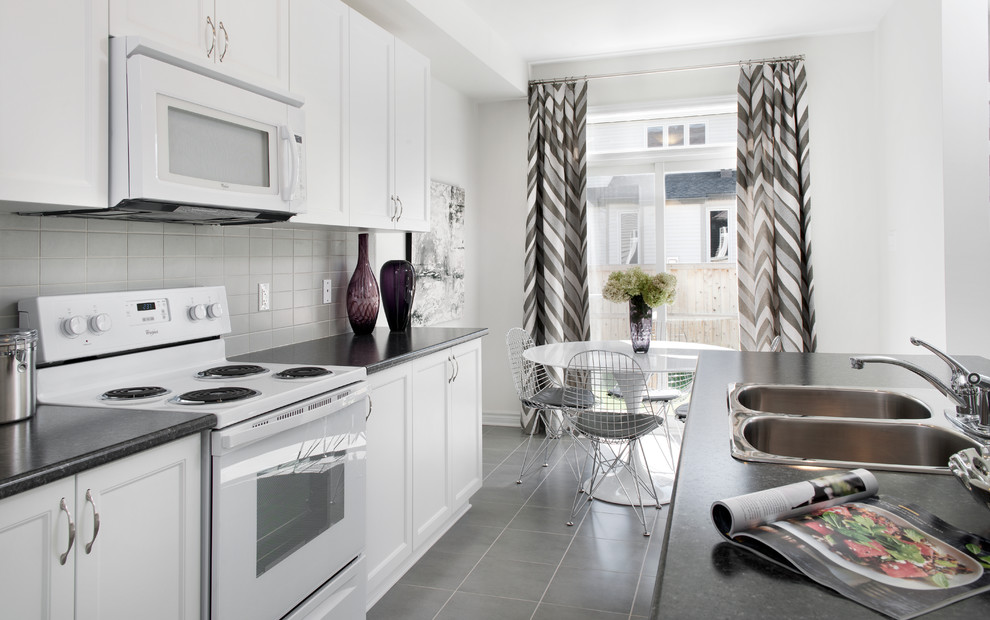 Immagine di una cucina minimal con lavello a doppia vasca, ante con riquadro incassato, ante bianche, paraspruzzi grigio e elettrodomestici bianchi