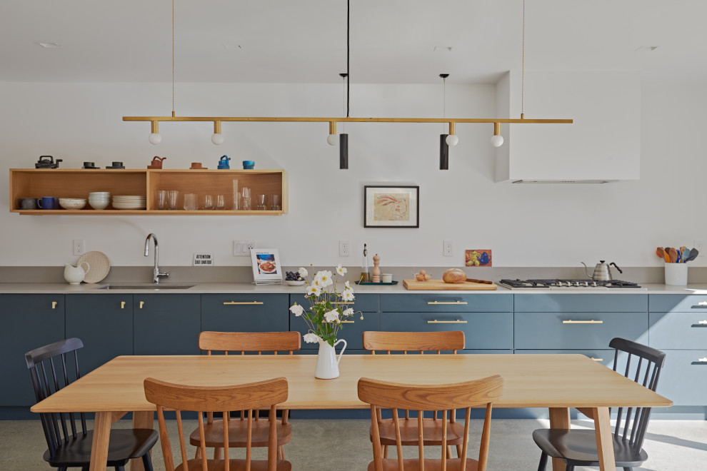 Источник вдохновения для домашнего уюта: прямая кухня в современном стиле с обеденным столом, врезной мойкой, плоскими фасадами, синими фасадами, бетонным полом, серым полом и серой столешницей без острова