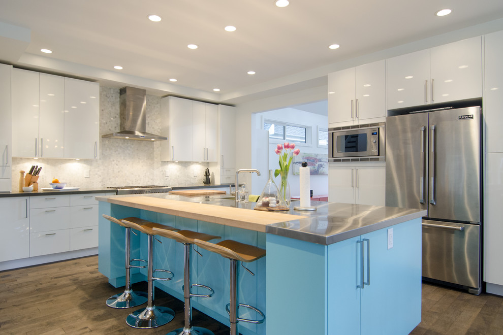 Moderne Küche mit flächenbündigen Schrankfronten, blauen Schränken, Edelstahl-Arbeitsplatte, Küchenrückwand in Weiß und Küchengeräten aus Edelstahl in Vancouver