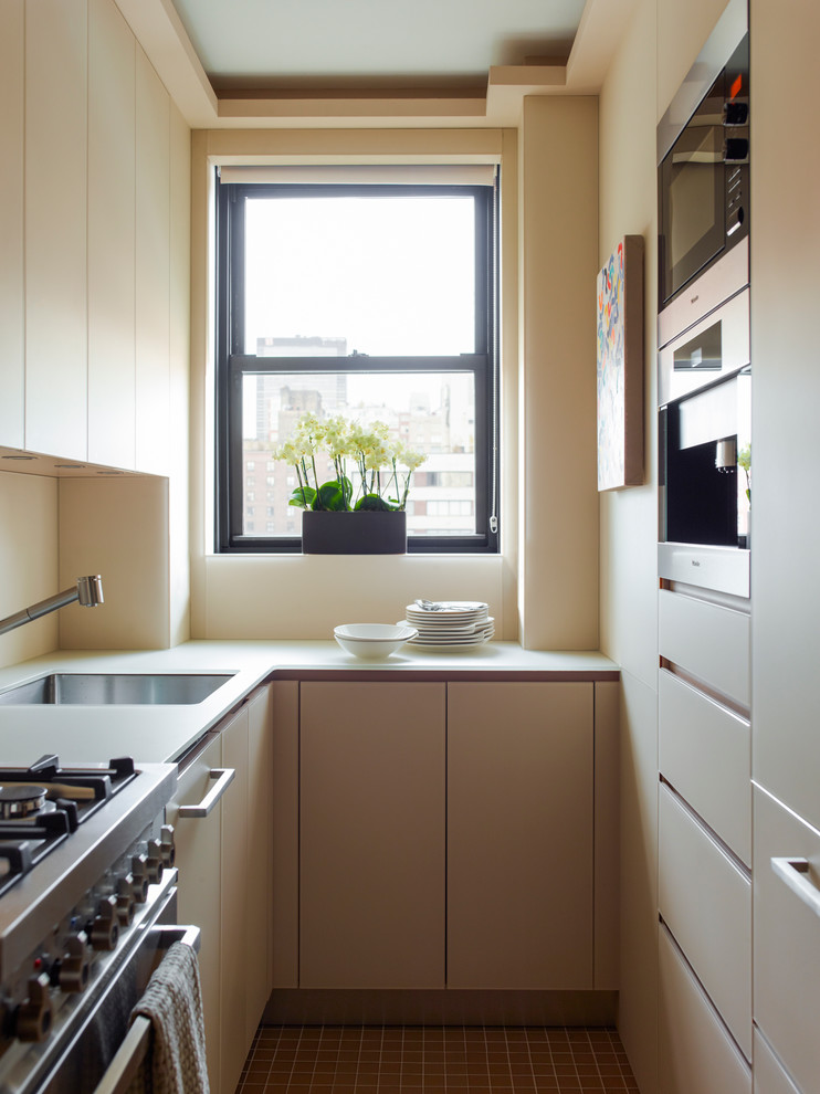 Zweizeilige, Kleine Moderne Küche mit Unterbauwaschbecken, flächenbündigen Schrankfronten, beigen Schränken, Küchengeräten aus Edelstahl und Küchenrückwand in Beige in New York