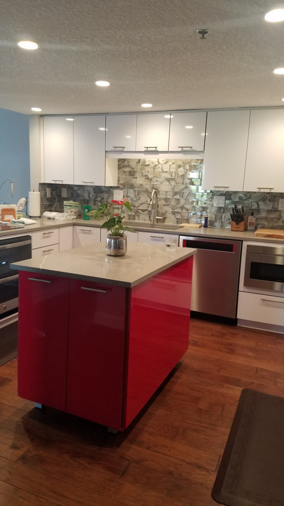 Photo of a medium sized modern u-shaped kitchen in Jacksonville with flat-panel cabinets, red cabinets, engineered stone countertops, beige splashback, marble splashback, stainless steel appliances, an island and beige worktops.