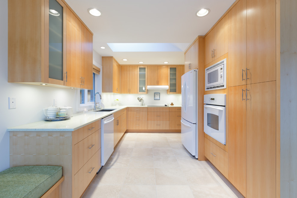 Bild på ett avskilt, mellanstort funkis l-kök, med en undermonterad diskho, släta luckor, skåp i ljust trä, bänkskiva i återvunnet glas, vitt stänkskydd, vita vitvaror och klinkergolv i porslin