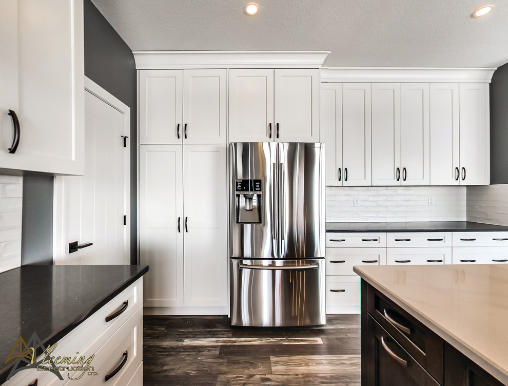 Inspiration for a mid-sized modern l-shaped dark wood floor eat-in kitchen remodel in San Diego with a double-bowl sink, shaker cabinets, white cabinets, solid surface countertops, white backsplash, subway tile backsplash, stainless steel appliances and an island