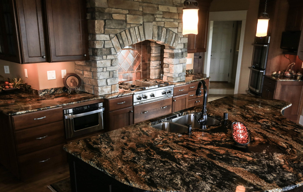 Example of a mid-sized mountain style galley medium tone wood floor eat-in kitchen design in Other with an island, shaker cabinets, dark wood cabinets, granite countertops, beige backsplash, stone tile backsplash and paneled appliances