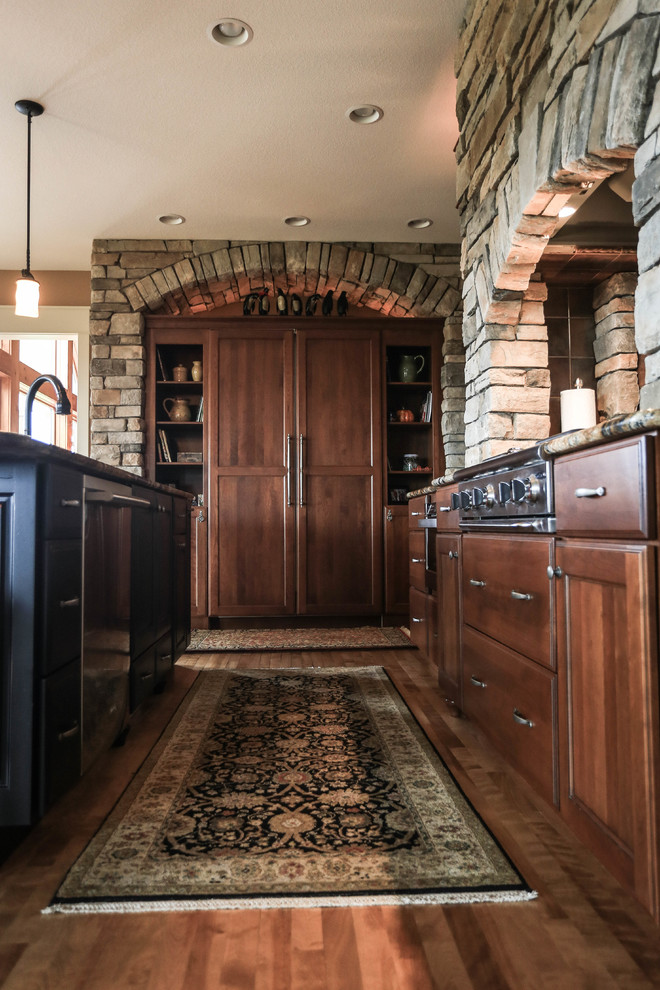 Immagine di una cucina rustica di medie dimensioni con ante in stile shaker, ante in legno bruno, top in granito, paraspruzzi beige, paraspruzzi con piastrelle in pietra, elettrodomestici da incasso e pavimento in legno massello medio