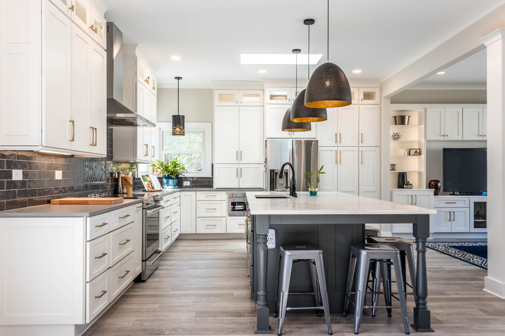Eat-in kitchen - large transitional l-shaped light wood floor and gray floor eat-in kitchen idea in Atlanta with white cabinets, black backsplash, porcelain backsplash, stainless steel appliances, an island, white countertops, an undermount sink and shaker cabinets
