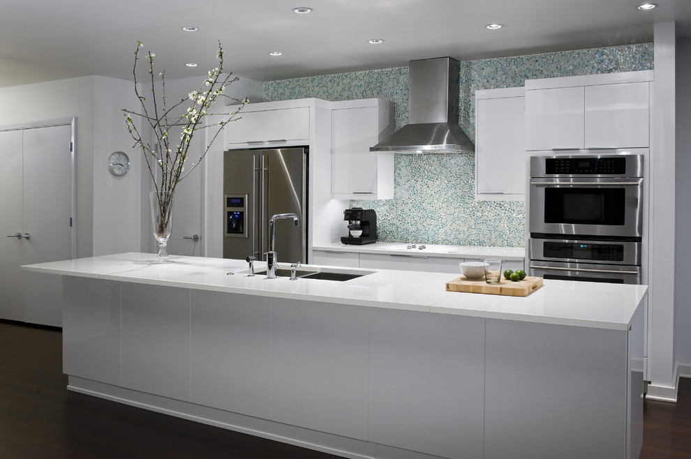 Photo of a contemporary galley open plan kitchen in Houston with a submerged sink, flat-panel cabinets, white cabinets, engineered stone countertops, multi-coloured splashback, mosaic tiled splashback, stainless steel appliances, dark hardwood flooring and an island.