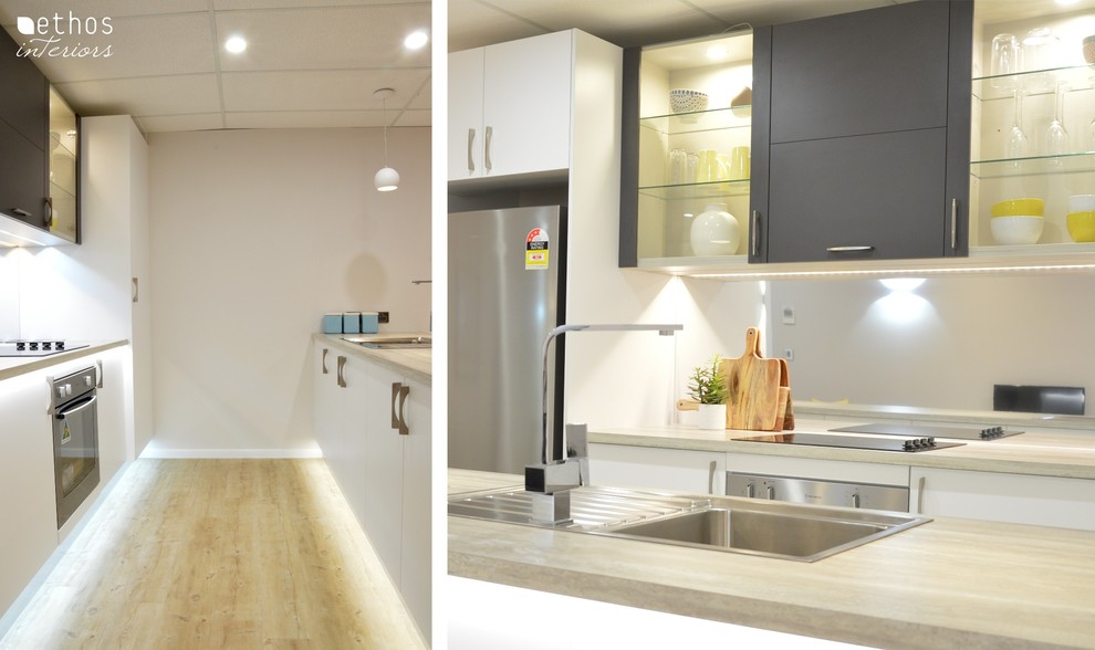 Exempel på ett litet modernt kök, med en enkel diskho, släta luckor, vita skåp, laminatbänkskiva, stänkskydd med metallisk yta, rostfria vitvaror, linoleumgolv och en köksö