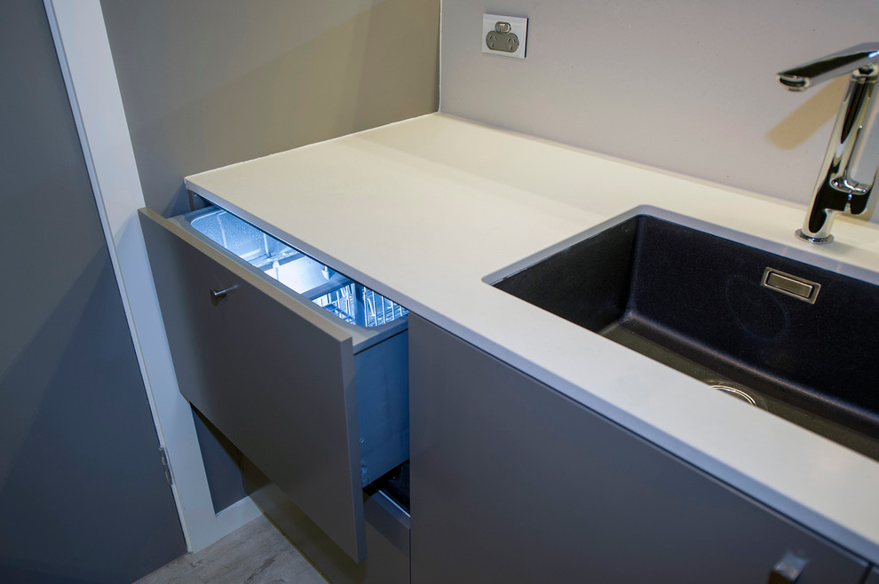 Enclosed kitchen - small contemporary galley light wood floor enclosed kitchen idea in Sydney with a single-bowl sink, flat-panel cabinets, solid surface countertops, mirror backsplash and no island
