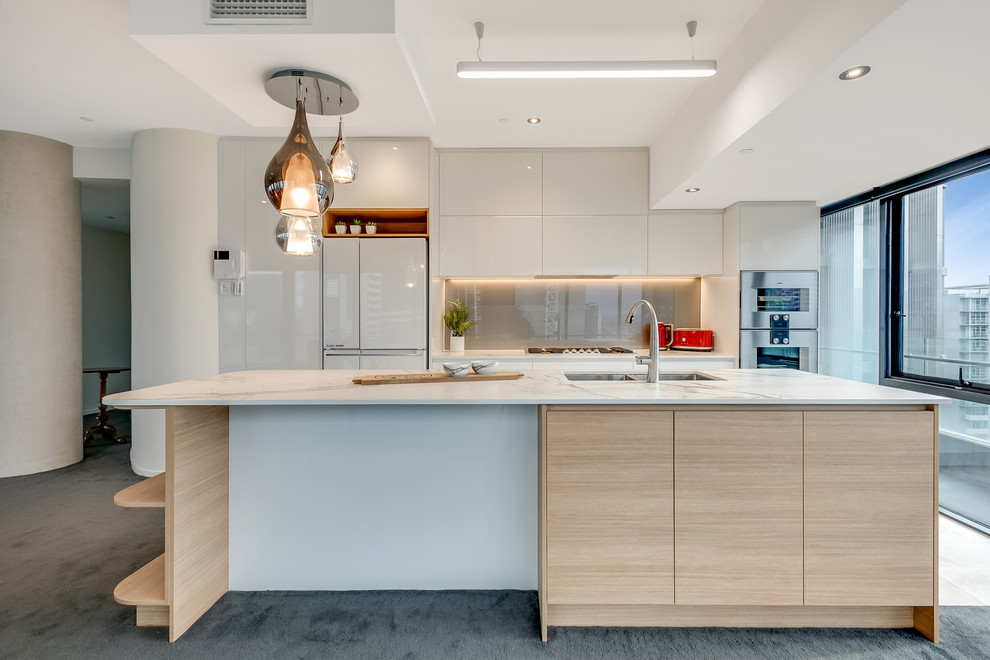 Photo of a medium sized modern single-wall kitchen/diner in Melbourne with flat-panel cabinets, white cabinets, engineered stone countertops, brown splashback, glass sheet splashback, white appliances and an island.